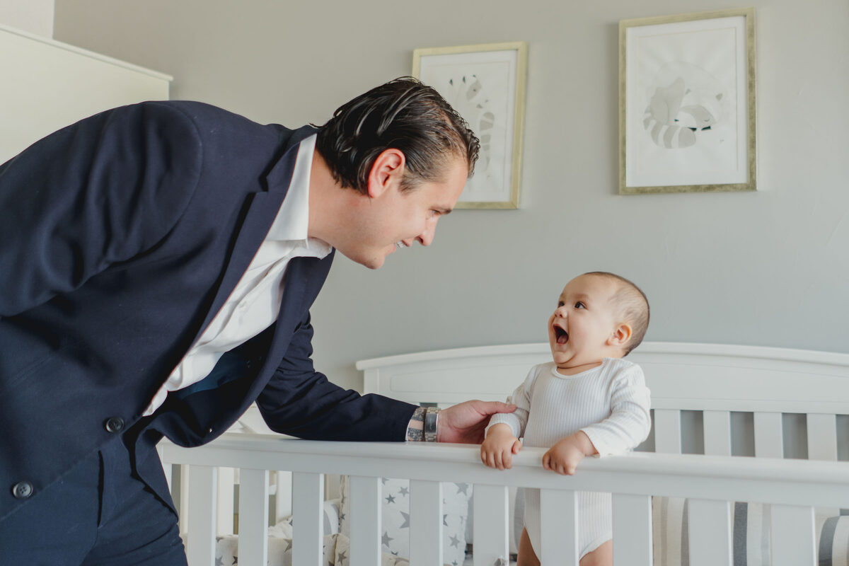 Papá y su bebé sonriendo en la cuna durante los preparativos